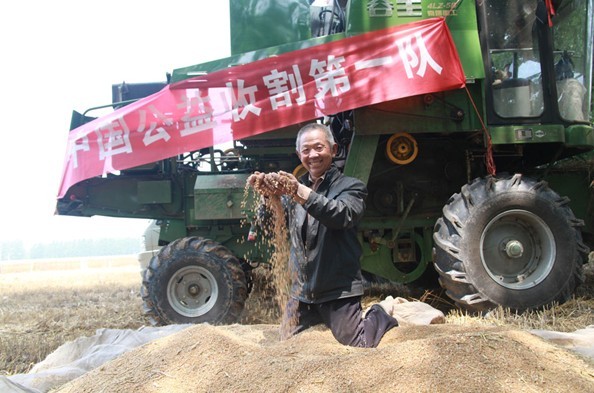 范连礼激动的捧起奇瑞重工公益收割队帮助收割的麦子