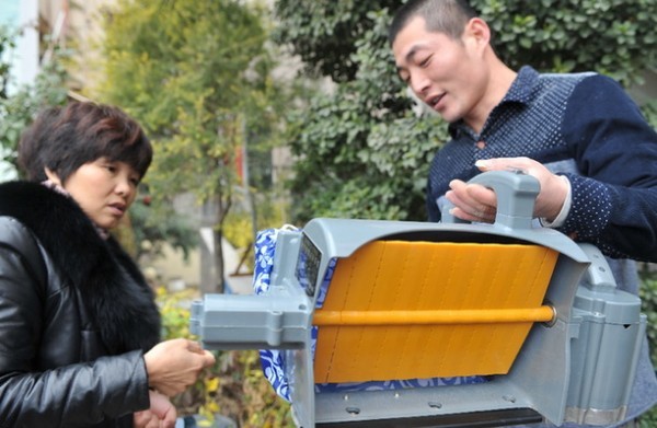厦门铂源机械制造有限公司工作人员黄进华在向湖南省经销商谢红英（左）介绍便捷式电动采茶机的第全新专利产品